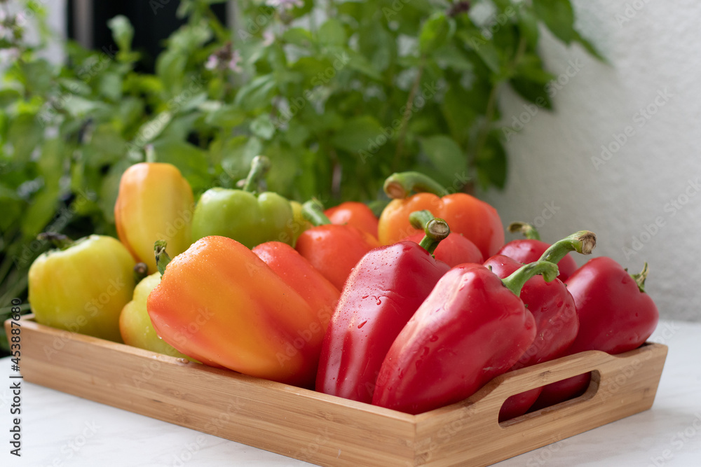 Sweet red pepper in a wooden tray on a white table