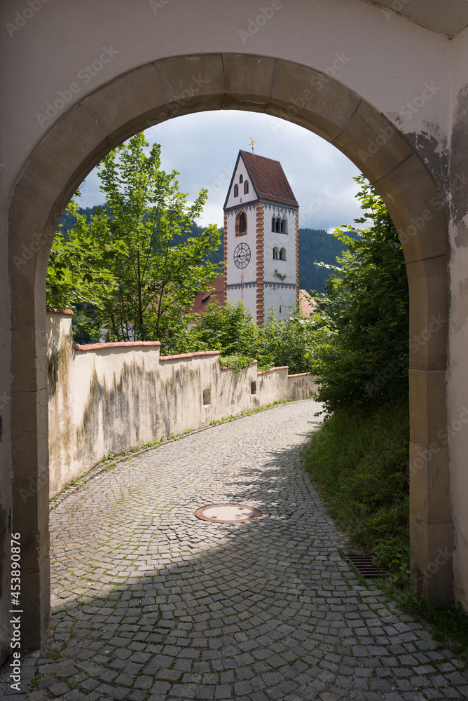 Fototapeta premium Catholic parish church of St. Mang through an arch in old town of Fussen, Bavaria, Germany