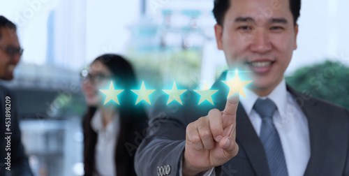 Businessman pointing five star symbol to increase rating of company. Business rating and teamwork concept.