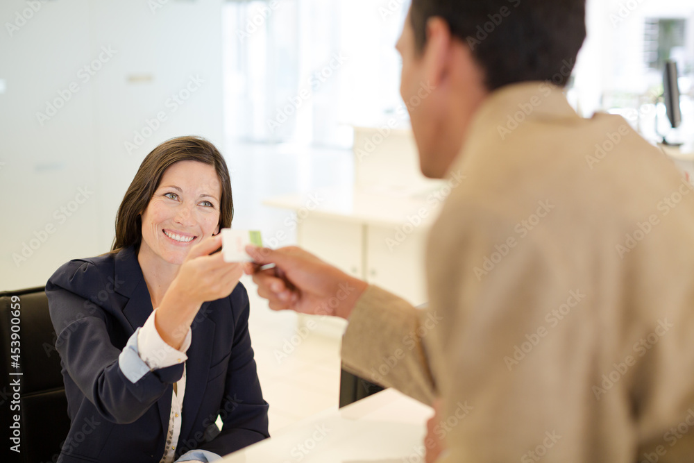 Businesswoman handing credit card to coworker Businesswoman handing credit card to coworker