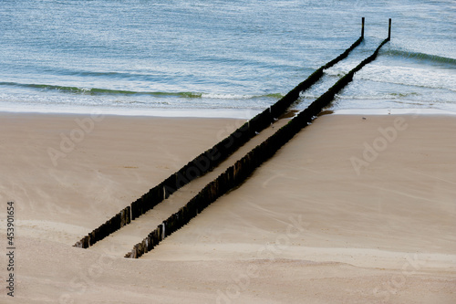 Minimalist view of the Dutch coastline with the water breakers during low tide of the North sea under an dramatic sky