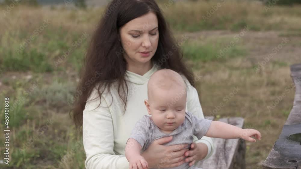 Portrait of caucasian mom with baby in her arms on a walk outdoors, adult mother with cute caucasian six month old baby boy on nature. High quality 4k footage Portrait of caucasian mom with baby in her arms on a walk outdoors, adult mother with cute caucasian six month old baby boy on nature. High quality 4k footage
