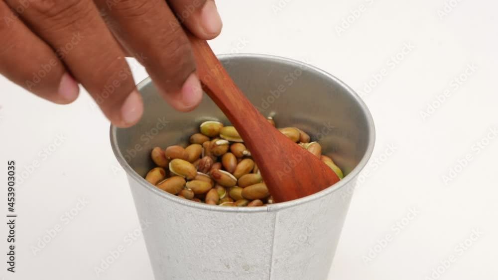 Moving wooden spoon in steel glass filled with beans seeds Moving wooden spoon in steel glass filled with beans seeds
