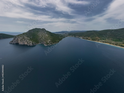 Aerial panoramic view of a Mediterranean coastline with a large body of water in the foreground and mountainous terrain