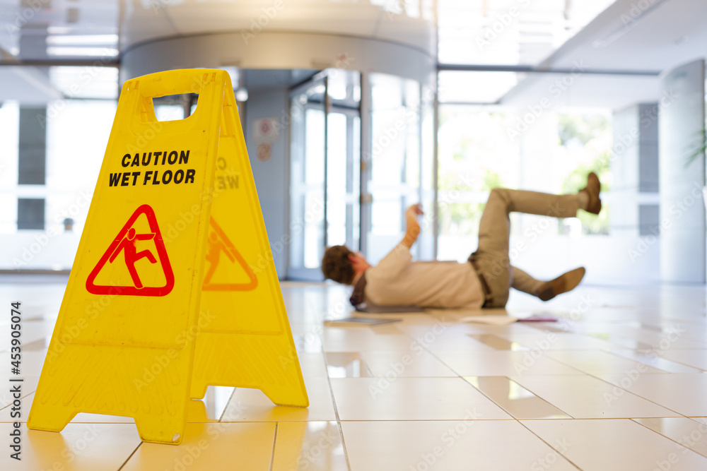 Businessman slipping on wet office floor - obrazy, fototapety, plakaty 