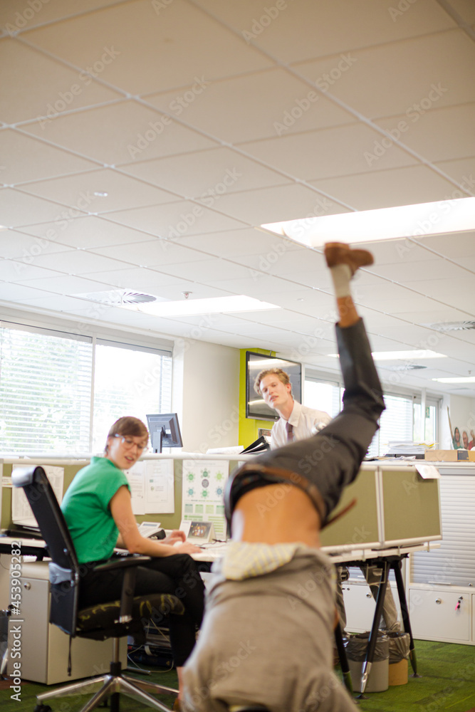 Businessman doing handstand in office Businessman doing handstand in office