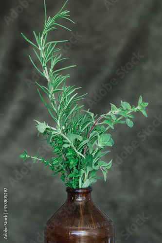 Stems of Thyme, Rosemary, and Oregano in a Brown Bottle