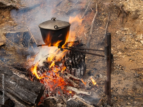 A black, smoked saucepan on the fire.