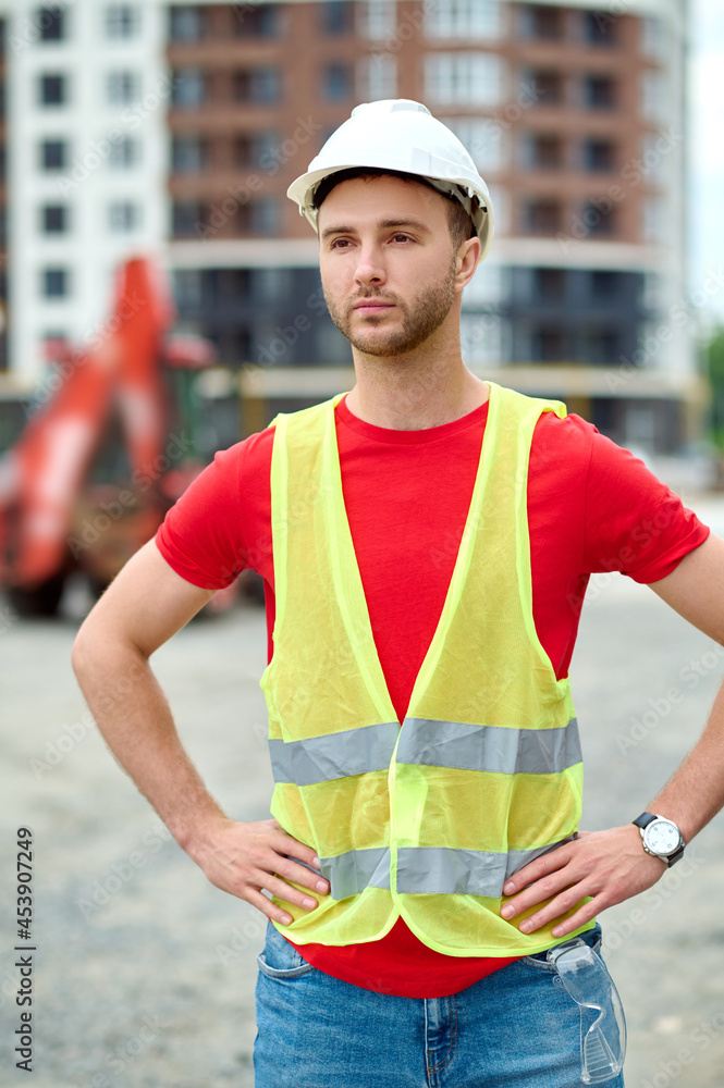 Worker in a safety vest and a helmet standing outdoors Worker in a safety vest and a helmet standing outdoors