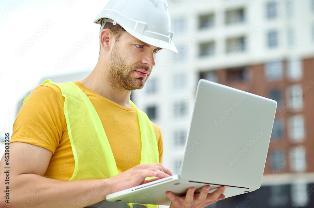 Concentrated male engineer working on his computer outdoors Concentrated male engineer working on his computer outdoors