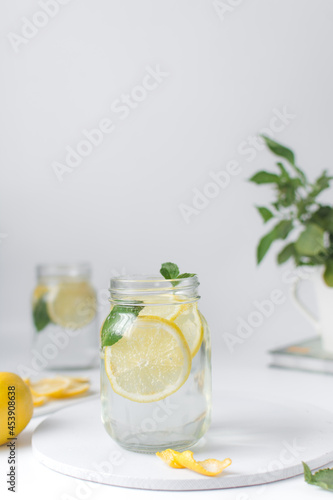 Lemon lime soda in a mason jar with a lemon slice and basil leaves, lemonade in a glass jar