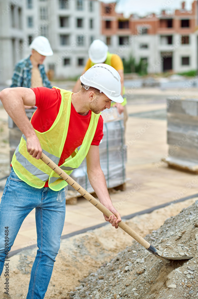 Industrious male worker digging the ground with a spade