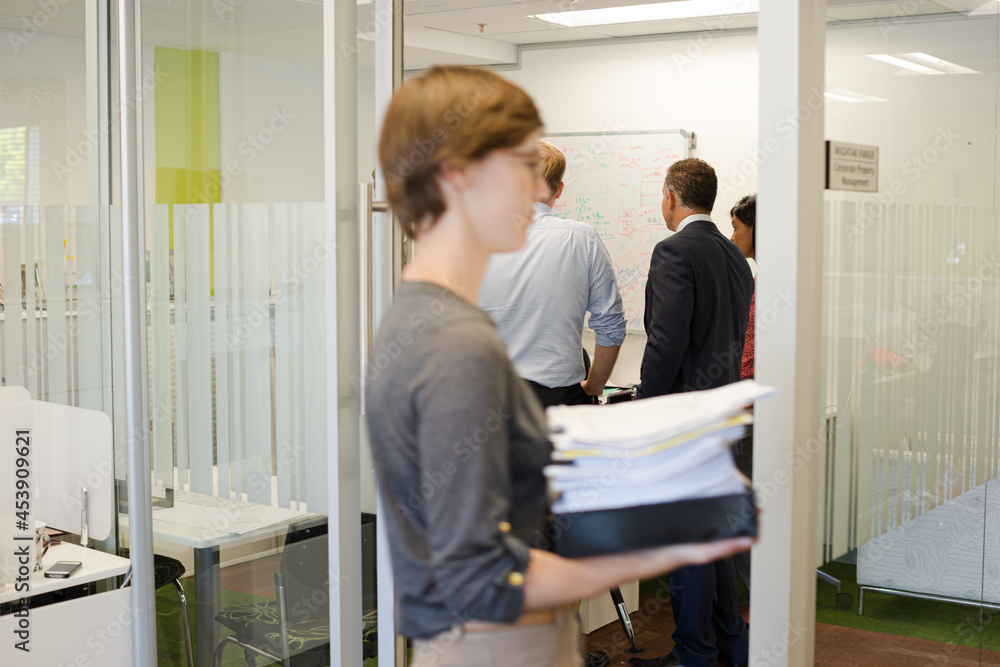 Obraz premium Businesswoman carrying pile of documents in office