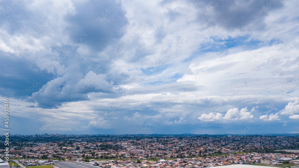 Drone image of bluish clouds, some rain formations, and the city at the bottom of the photo
