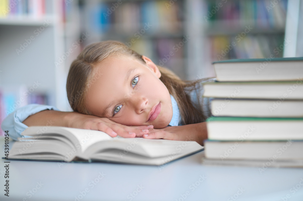Exhausted schoolchild lying on her library textbook Exhausted schoolchild lying on her library textbook