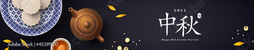 White snow mooncakes on porcelain plate, teapot and teacup. Chinese translation is blessing and Mid Autumn. Flat lay of tea ceremony with cookies, pot and yellow petals. China holiday poster, header.