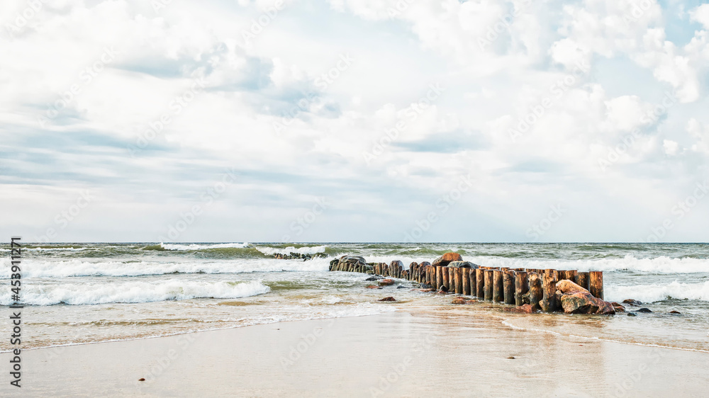 An old breakwater of logs and stones in the undulating Baltic Sea against the background of a dramatic sky An old breakwater of logs and stones in the undulating Baltic Sea against the background of a dramatic sky