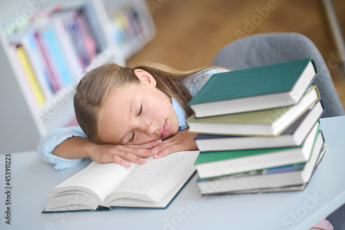 Fototapeta Tired pupil dozing on an open textbook