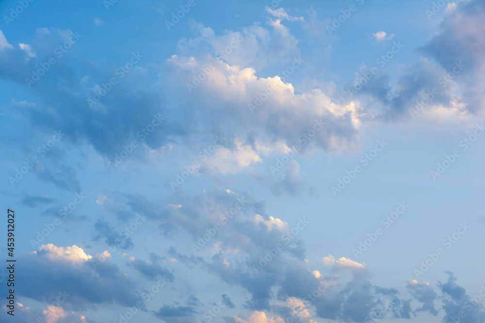 Evening blue sky with clouds at sunset. Clouds are illuminated by the rays of the setting sun. Evening blue sky with clouds at sunset. Clouds are illuminated by the rays of the setting sun.