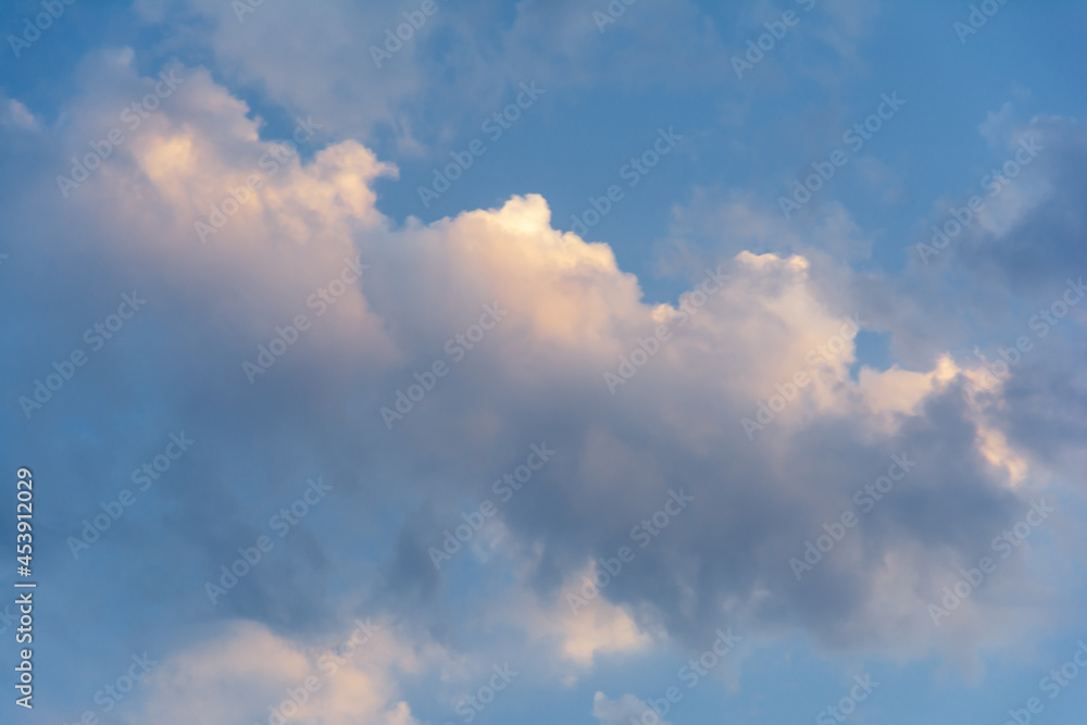 Evening blue sky with clouds at sunset. Clouds are illuminated by the rays of the setting sun.