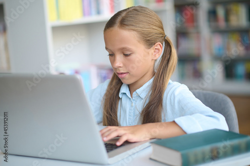 Focused young girl using a gadget in learning