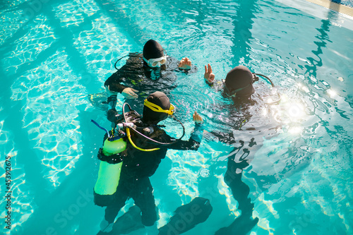 Divemaster and divers in aqualungs, diving school photo