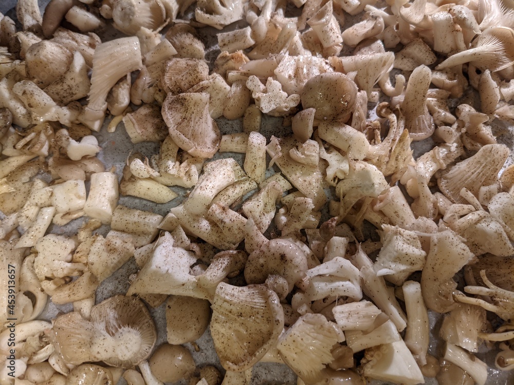chopped oyster mushrooms on a baking sheet with spices and pepper before cooking