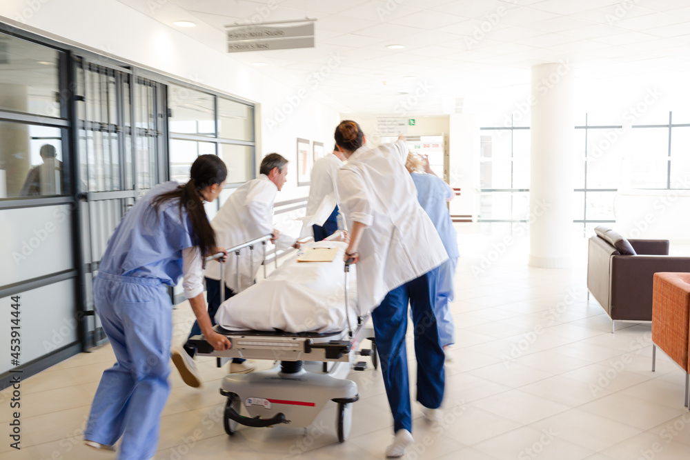 Obraz premium Doctors rushing patient on gurney in hospital corridor