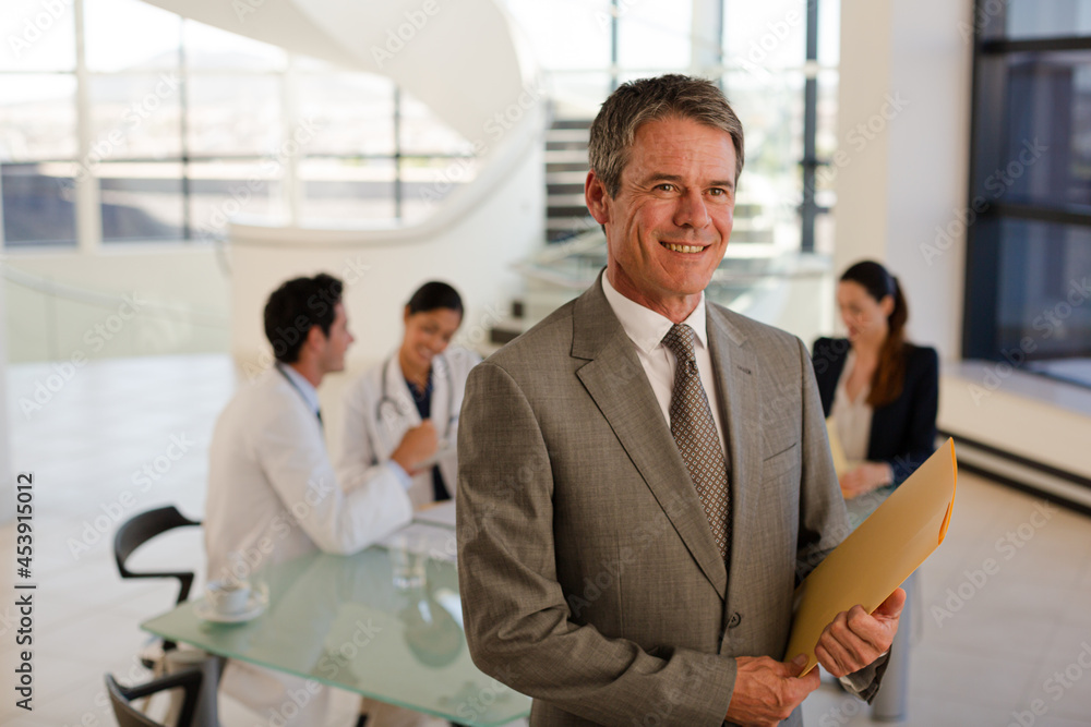 Portrait of smiling businessman in meeting with doctors Portrait of smiling businessman in meeting with doctors