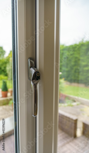 close up of modern double glazed matt chrome metal double glazed window handle with key lock