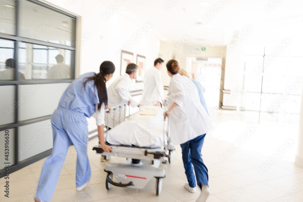 Doctors rushing patient on gurney in hospital corridor Doctors rushing patient on gurney in hospital corridor