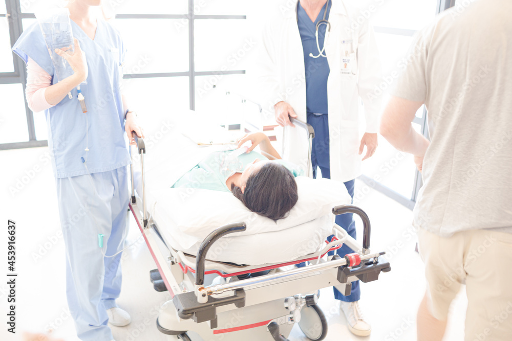 Obraz premium Doctors rushing patient on gurney in hospital corridor