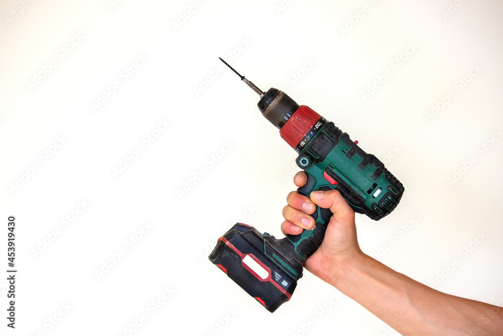 Hand with cordless screwdriver and drill isolated on white background. Twists screws into the board. Hand with cordless screwdriver and drill isolated on white background. Twists screws into the board.