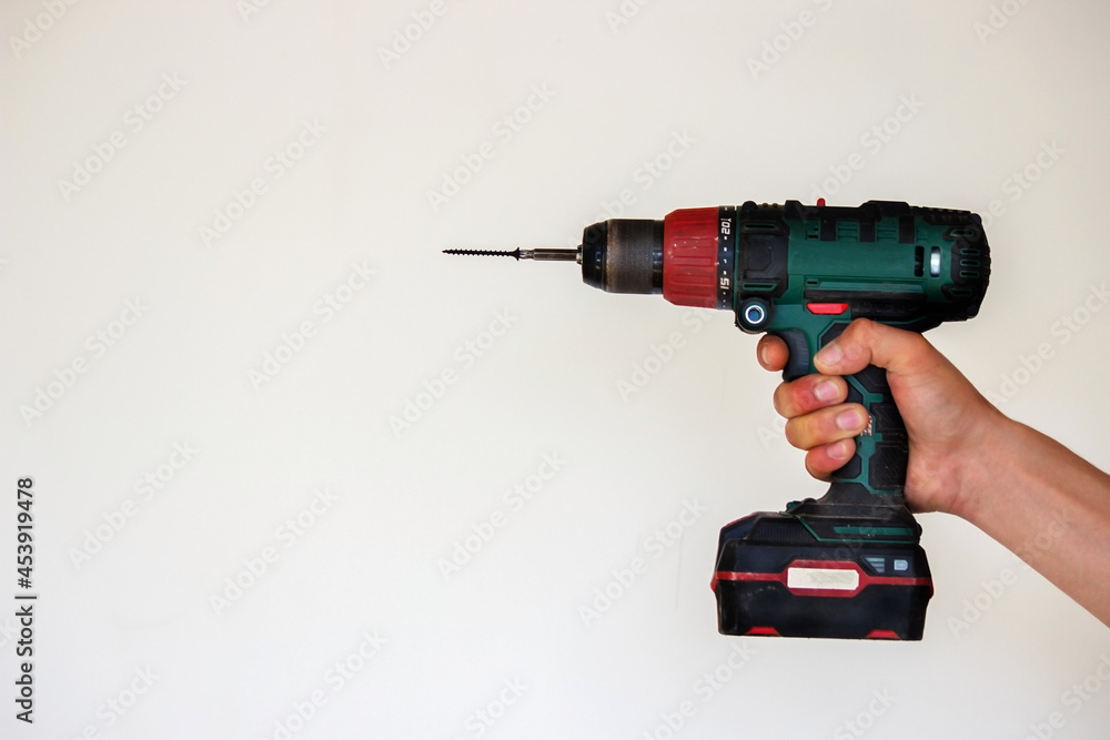 Hand with cordless screwdriver and drill isolated on white background. Twists screws into the board. Hand with cordless screwdriver and drill isolated on white background. Twists screws into the board.