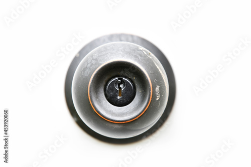 A close up image of the key hole on a black door knob with a white background. 