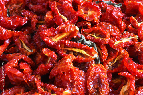 A close up image of sun dried cherry tomatoes with dried basil leaves. 