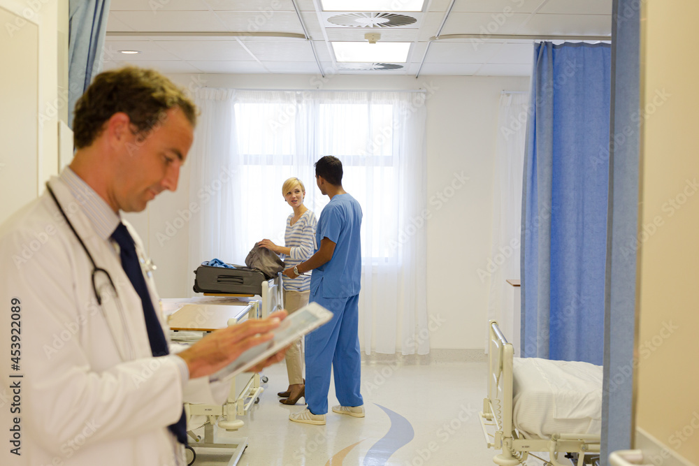 Fototapeta premium Doctor reading clipboard in hospital room