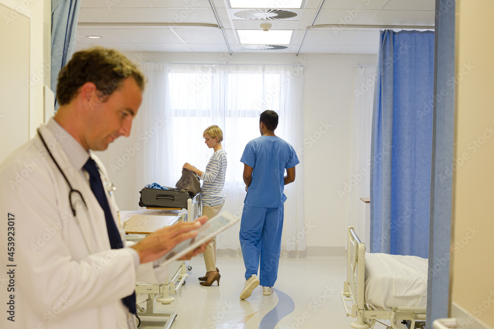 Obraz premium Doctor reading clipboard in hospital room