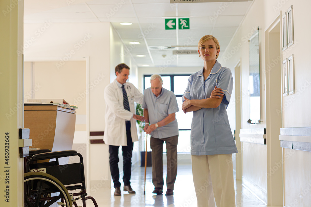 Doctor and nurse standing with patient in hospital hallway