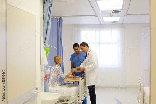 Doctor and nurse talking to patient in hospital room © KOTO