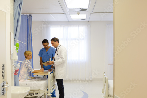 Doctor and nurse talking to patient in hospital room © KOTO