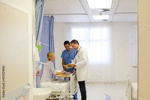 Doctor and nurse talking to patient in hospital room