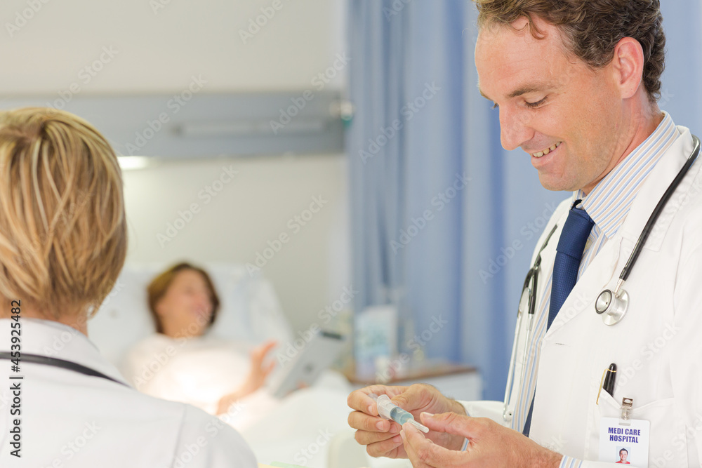 Fototapeta premium Doctor checking syringe in hospital room