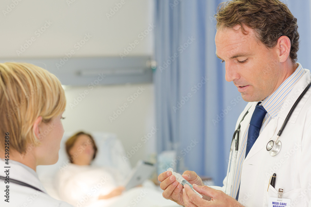 Fototapeta premium Doctor checking syringe in hospital room