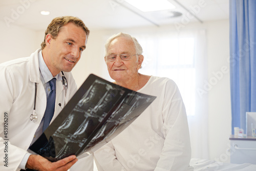 Doctor showing x-rays to older patient in hospital room