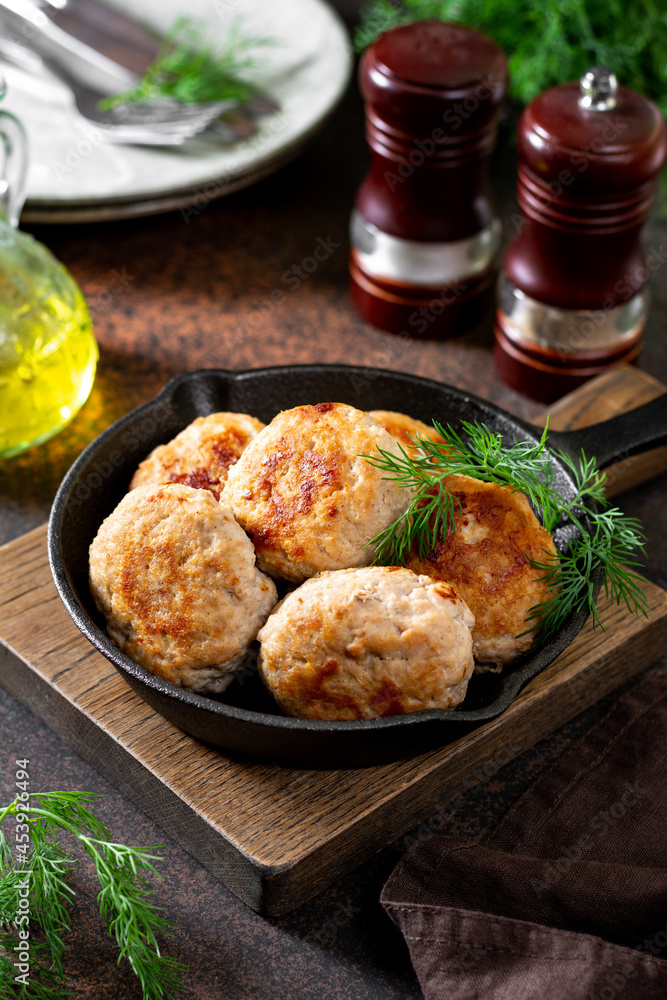 Turkey meat cutlets in a black frying pan on a brown cooking table close-up Turkey meat cutlets in a black frying pan on a brown cooking table close-up