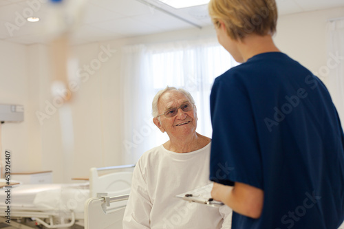 Nurse and older patient talking in hospital room