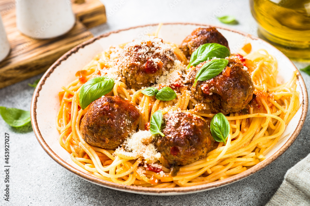Pasta with Meatballs in tomato sauce, basil and parmesan on light stone table. Pasta with Meatballs in tomato sauce, basil and parmesan on light stone table.