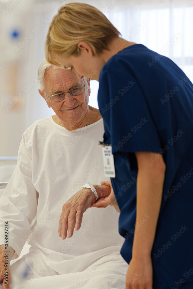 Nurse reading older patient's medical bracelet in hospital Nurse reading older patient's medical bracelet in hospital