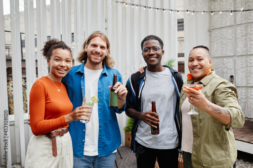 Diverse group of modern young people looking at camera while having fun at outdoor rooftop party